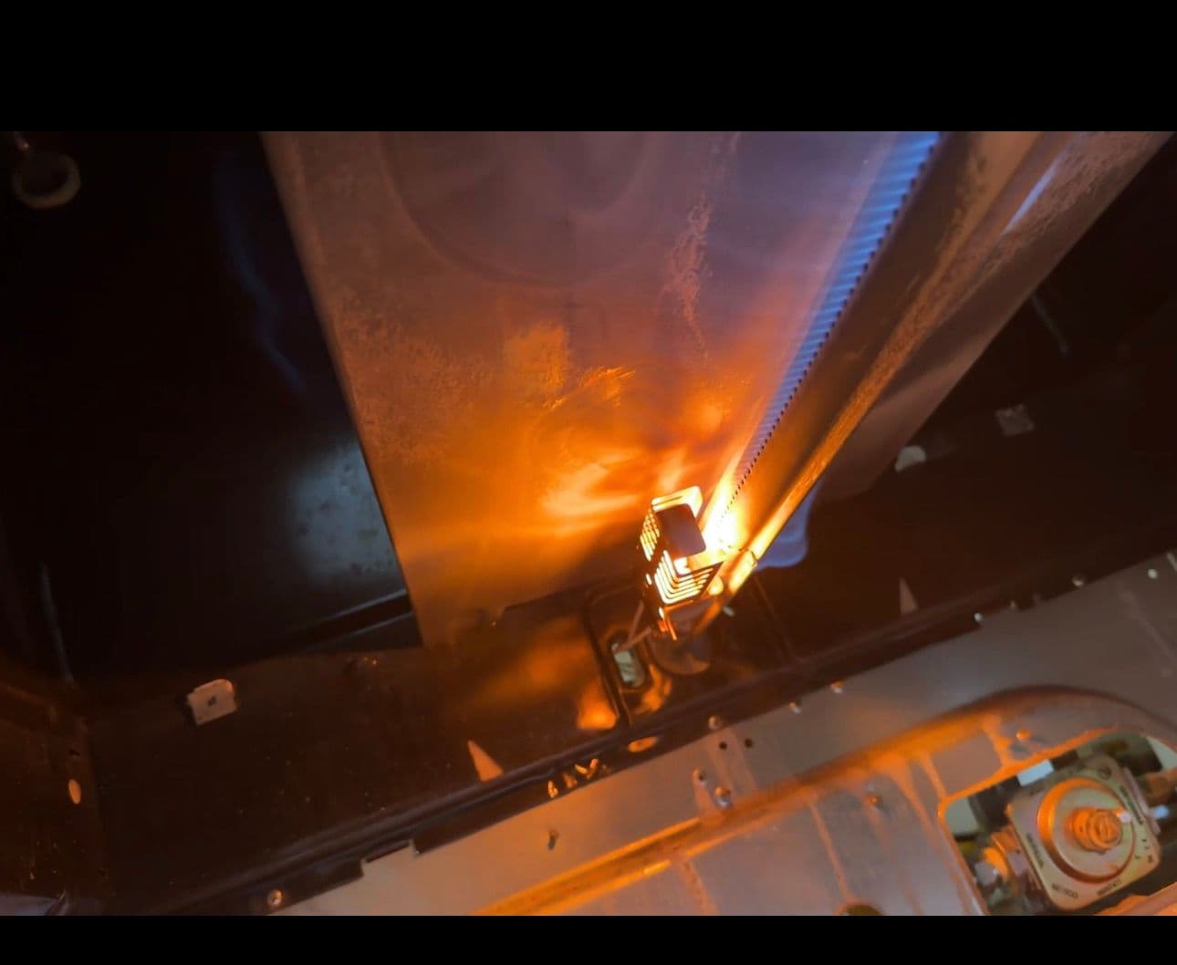 Orange flame from a gas dryer burner assembly firing inside the dryer cabinet