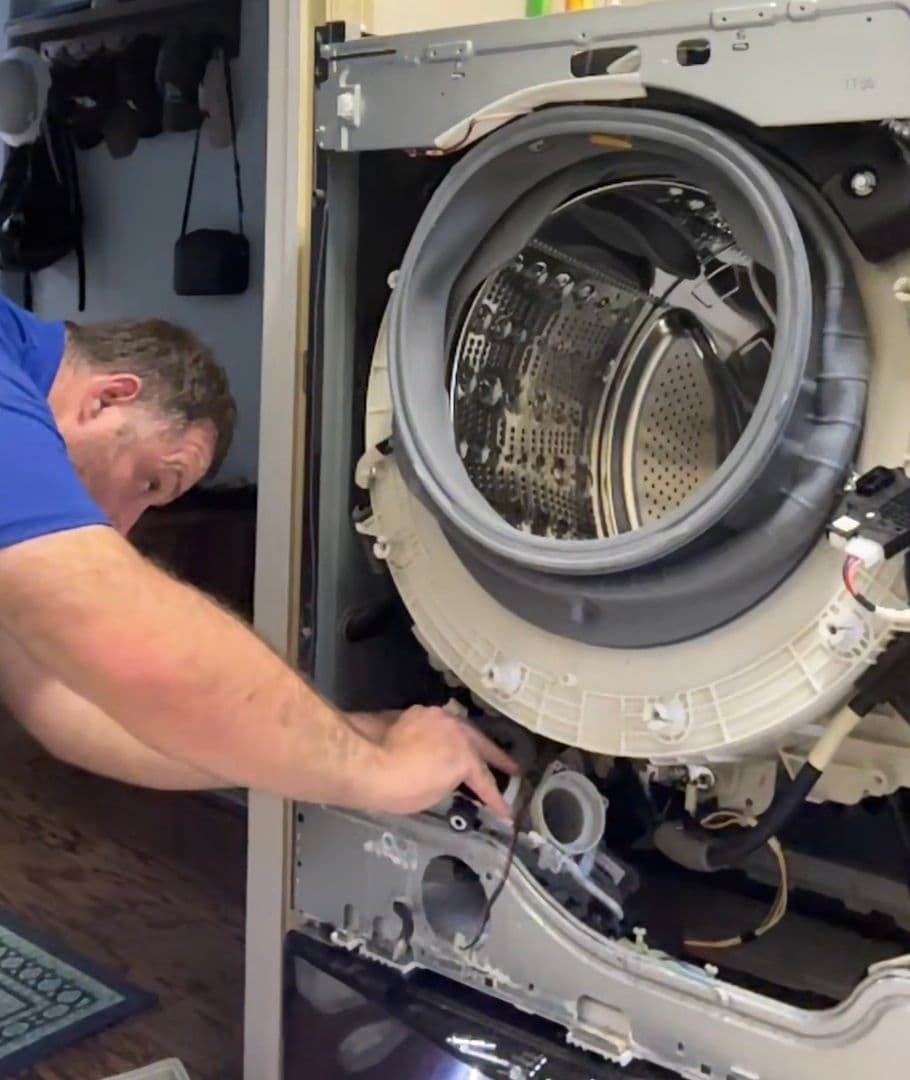 Jason working inside an opened front-load washer with the drum and tub exposed